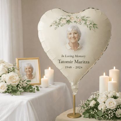 Personalised Heart-shaped balloon with a photo of an elderly woman and memorial text, surrounded by flowers and candles on a table.