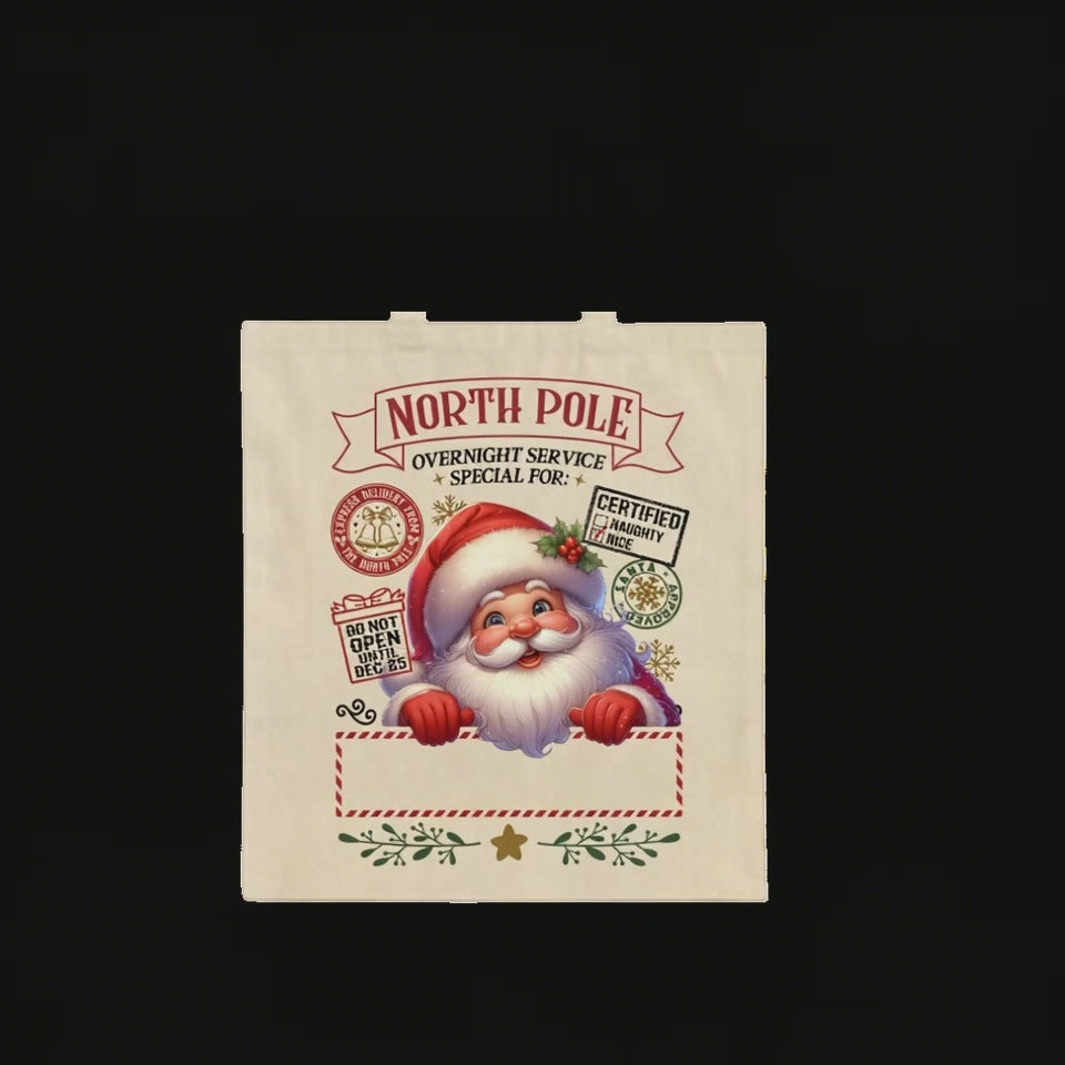 Top-down video of a North Pole Santa tote bag on a wooden table, with a woman’s hands placing small wrapped gifts, a candy cane, and a white coffee cup on it. A child’s hand briefly takes a candy, creating a cozy Christmas family moment.